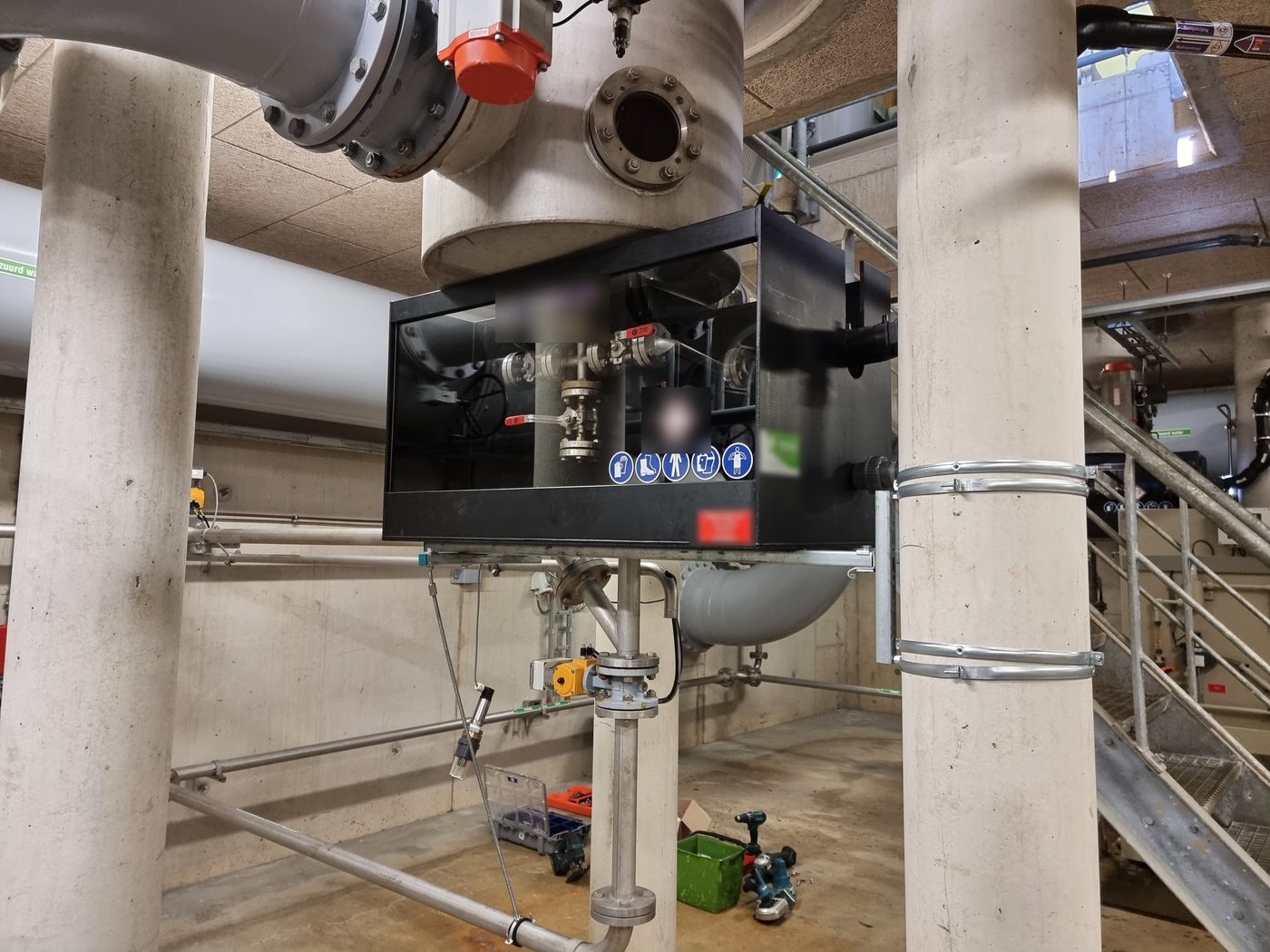 Zwarte kast met Lexan raam aan een vat in de technische ruimte, met kleppen en leidingen erin