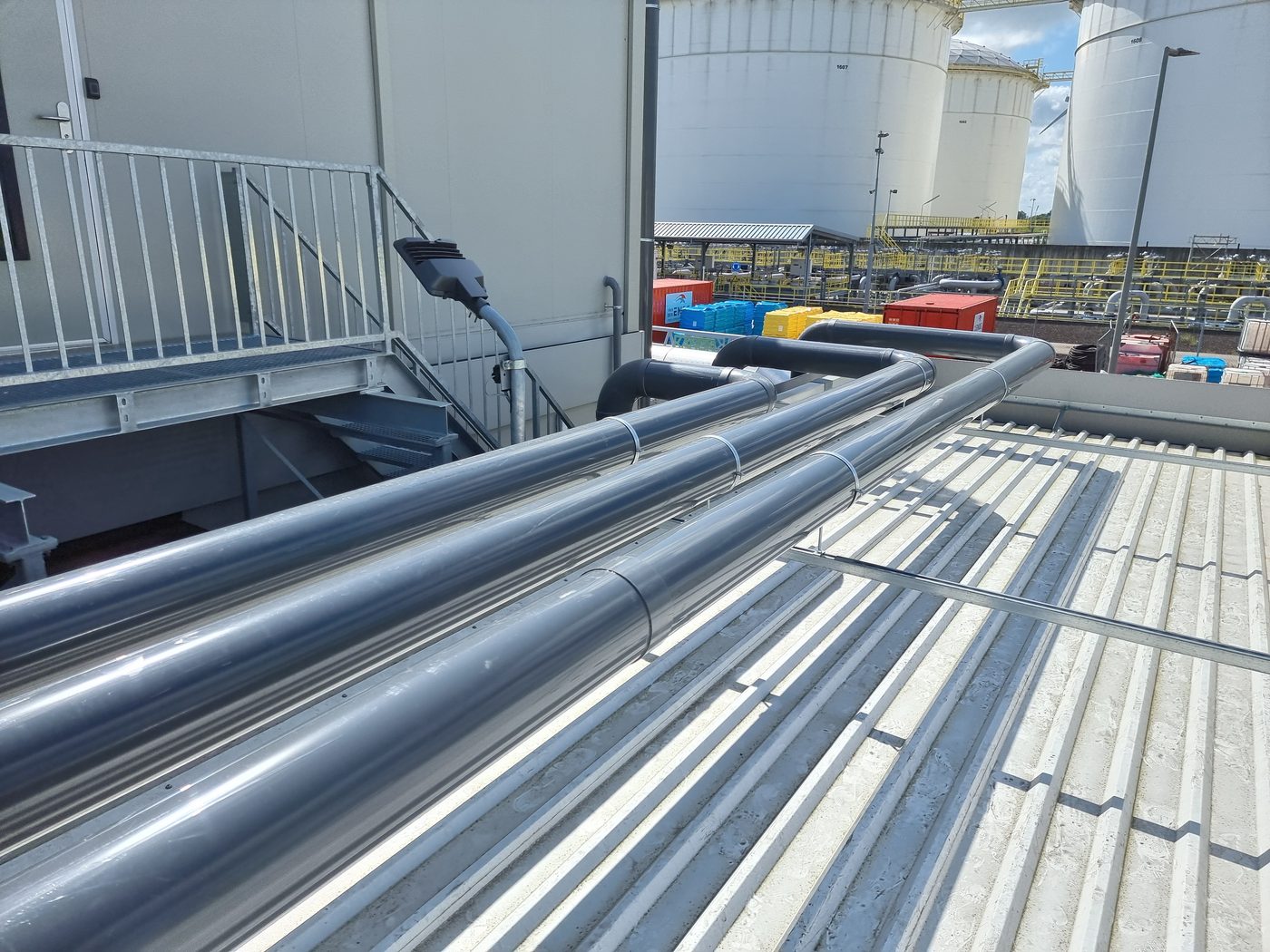 Drie parallelle PVC-leidingen op het dak, vastgezet met beugels
