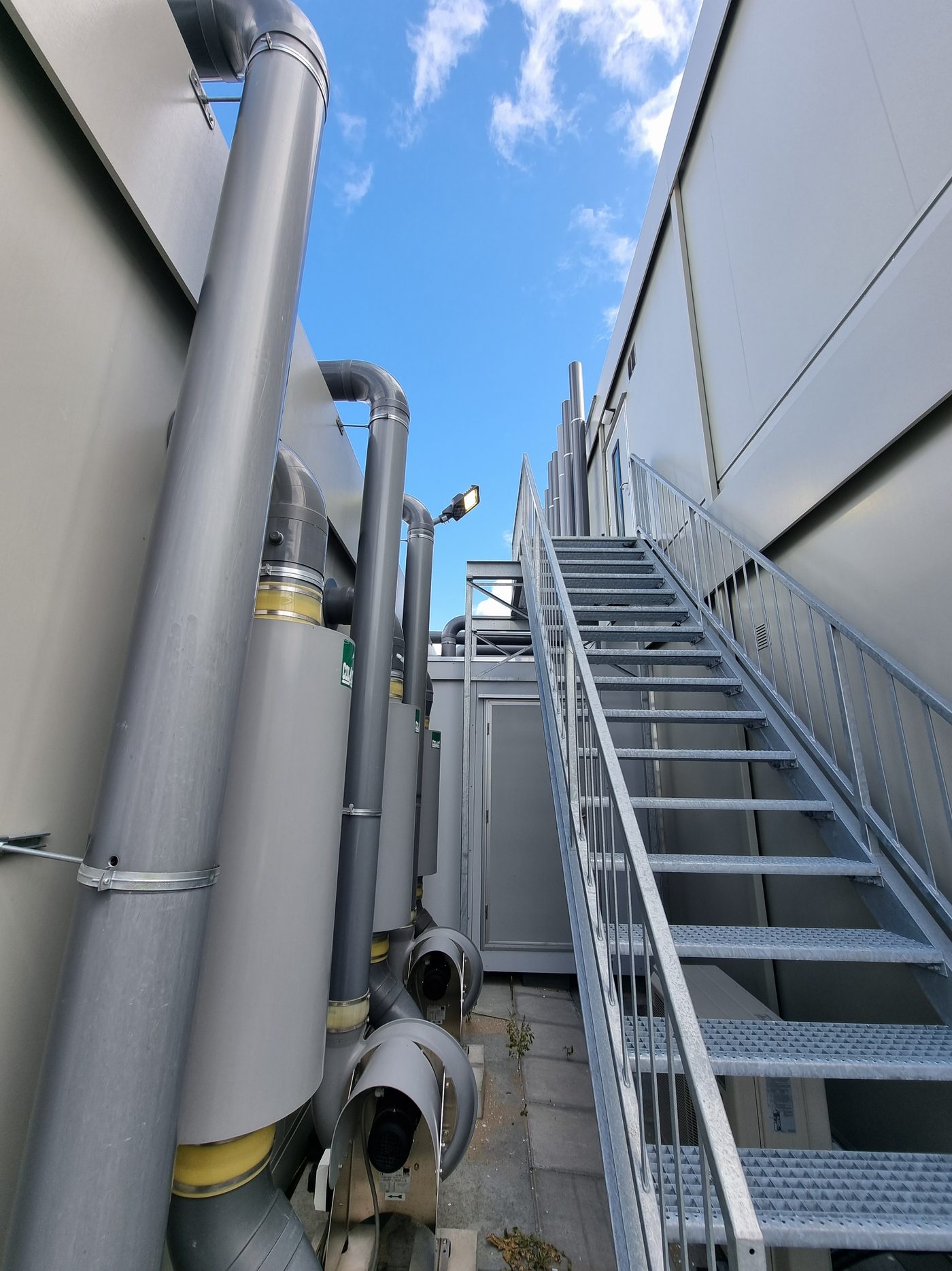PVC-afzuigleidingen met dempers en slakkenhuisventilatoren langs de gevel