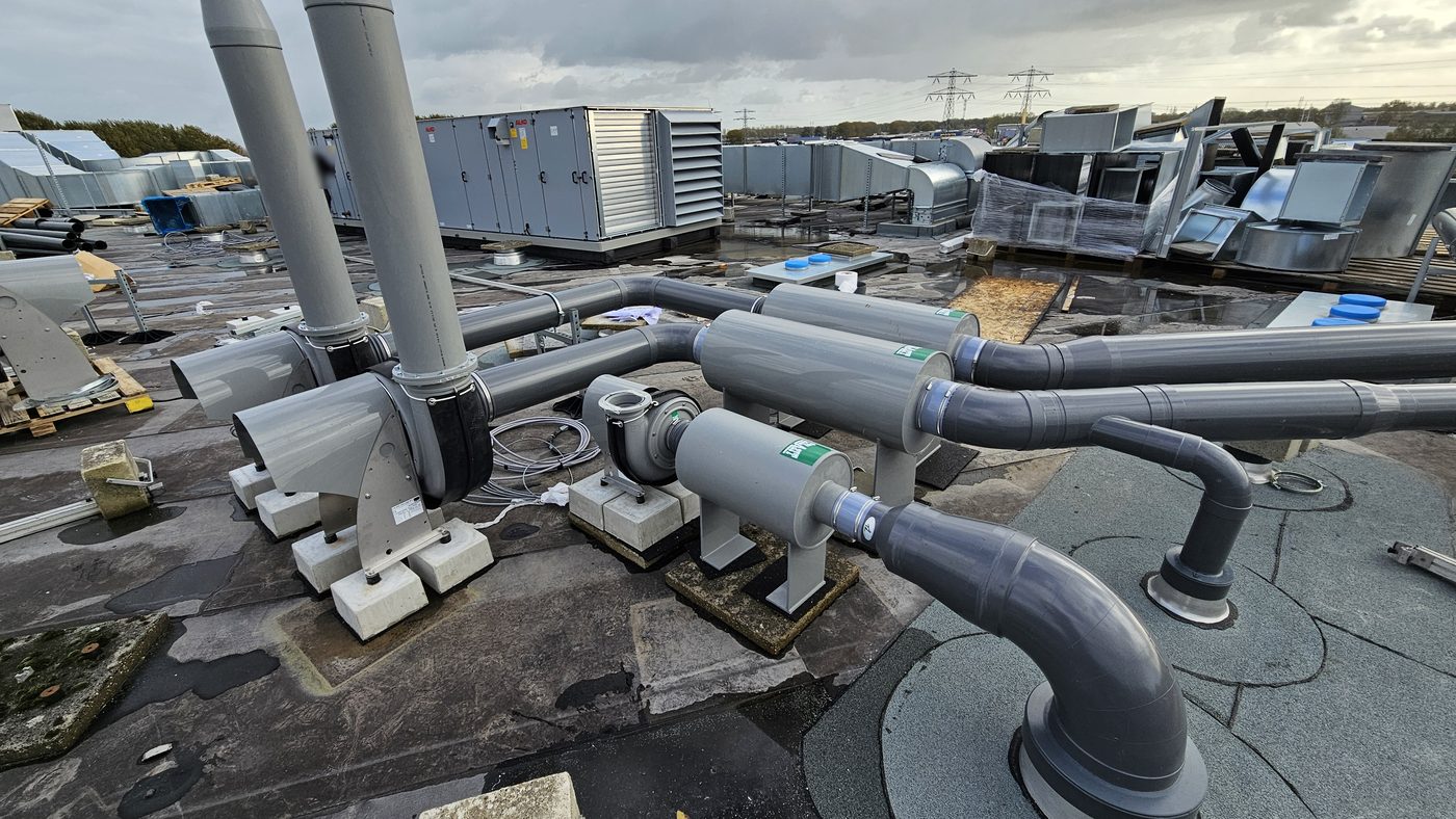 Ventilatoren, dempers en PVC-afzuigleidingen op het dak van de school