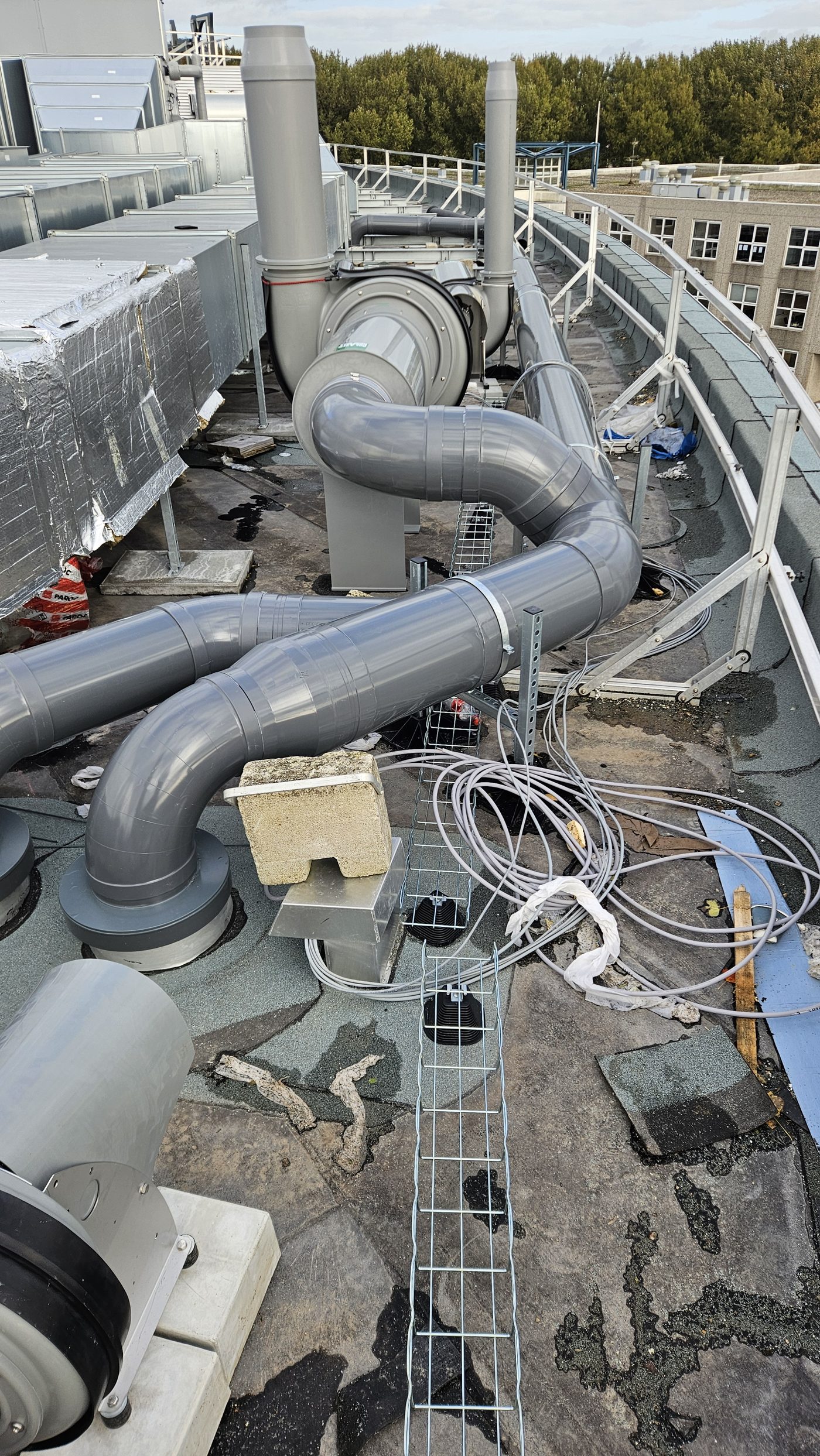 PVC-leidingwerk in bochten op het dak, naar de dempers en ventilatoren