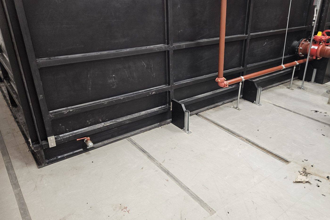 Onderkant van de tank met aftapkraan, naast de leidingen van de blusinstallatie