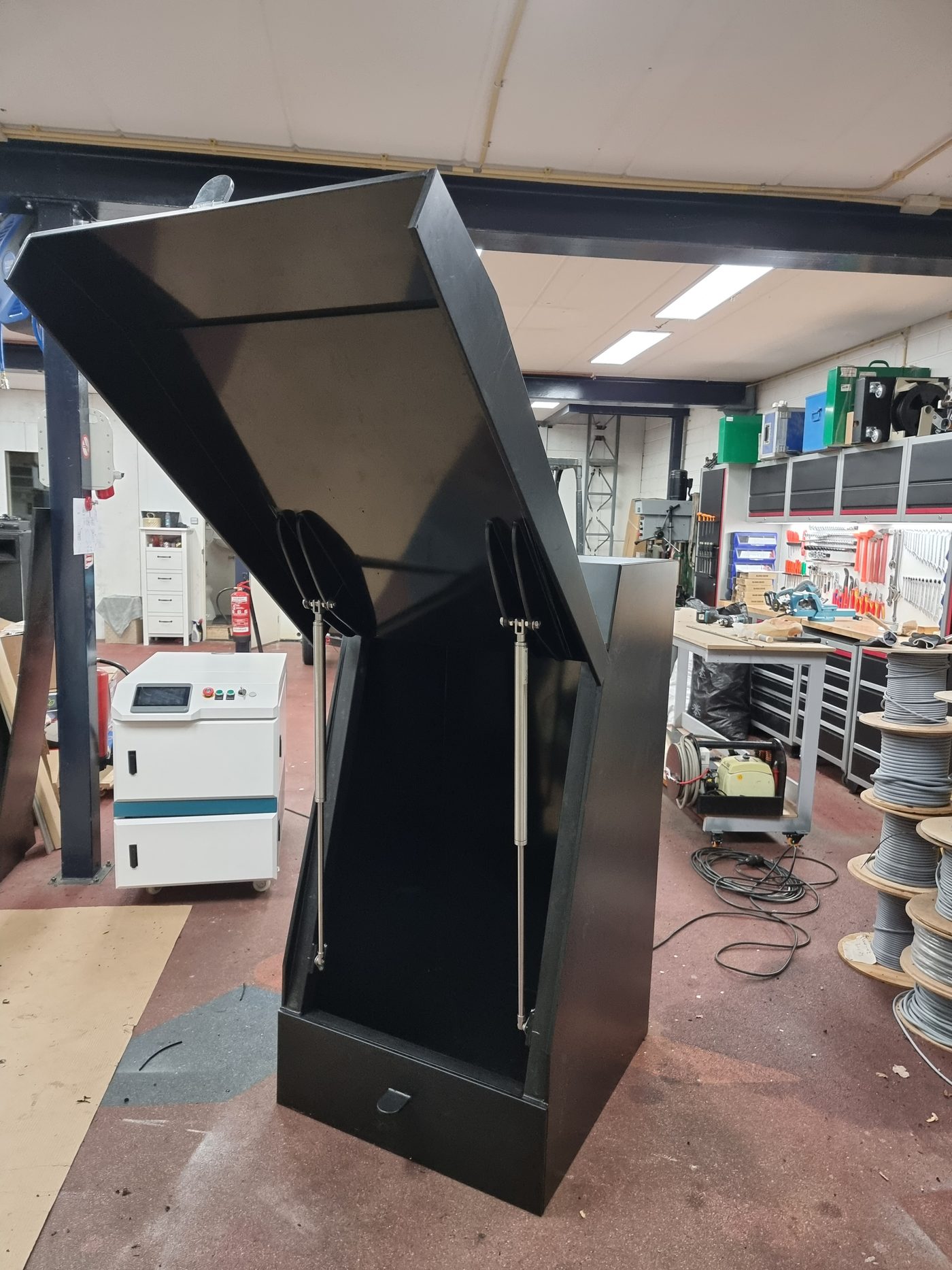 Vulpuntkast in de werkplaats, met het deksel open op RVS gasveren